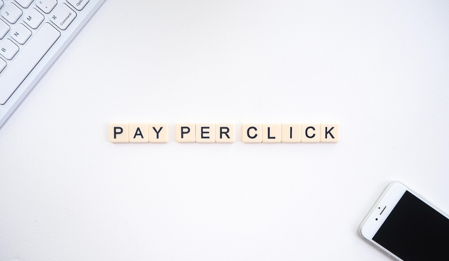 Alphabet tiles spell "PAY PER CLICK" on a white surface.